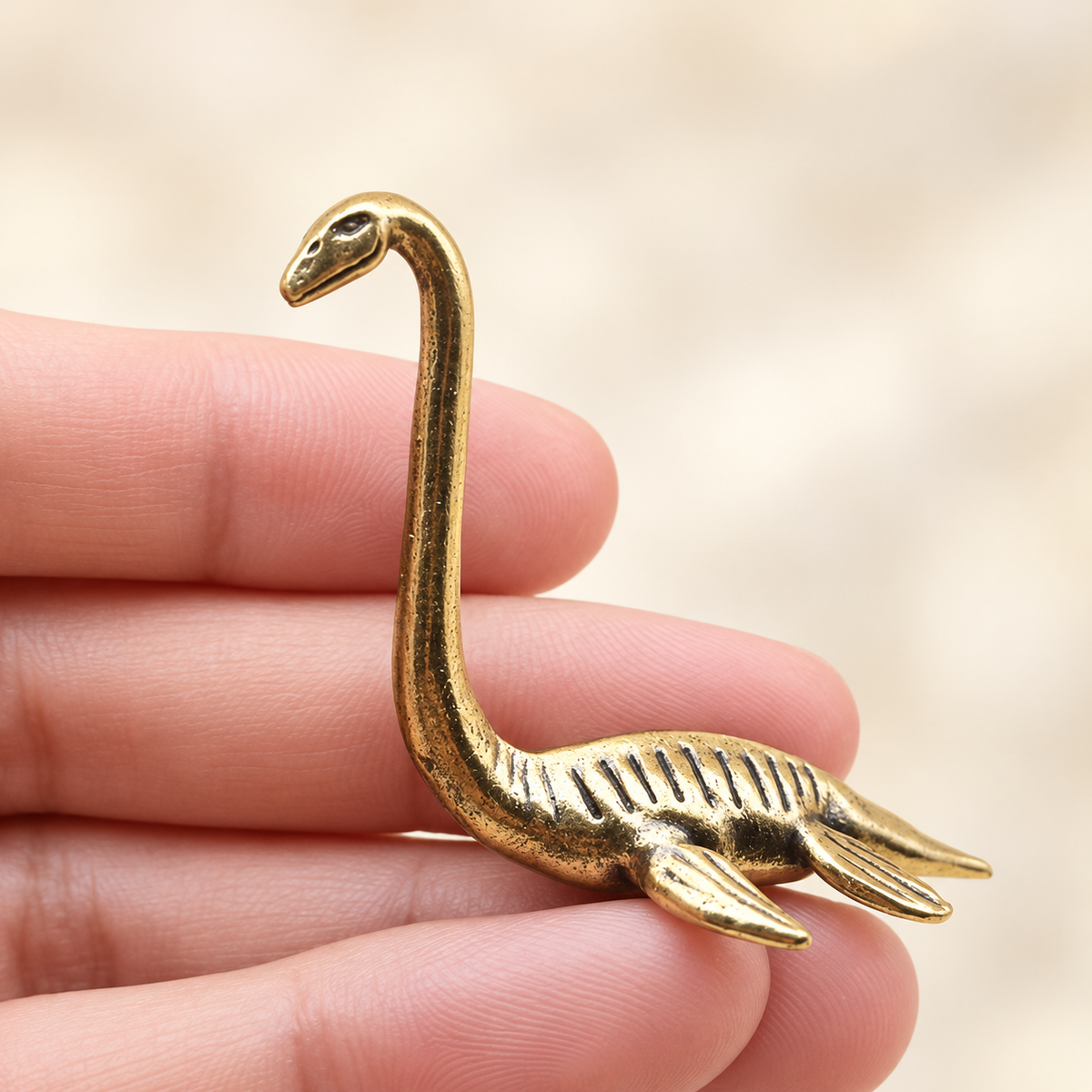 Miniature gold-toned Champ the Lake Monster figurine held in a hand for scale
