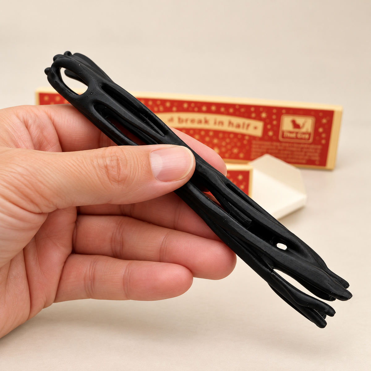 Close-up of black 3D-printed ONE WISH WILLOW toy held in a bare hand for scale